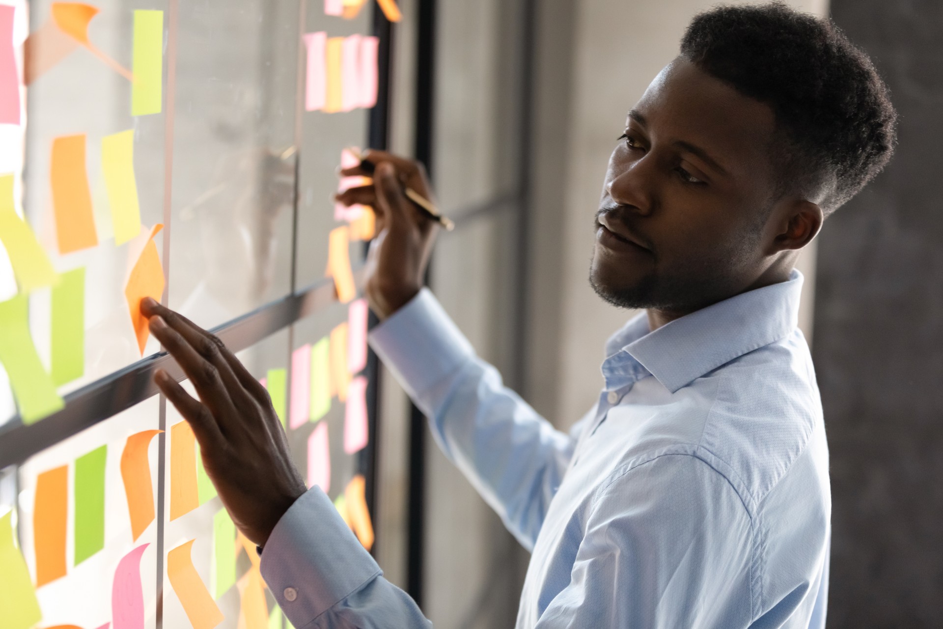 Serious african american businessmen managing project tasks on sticky notes